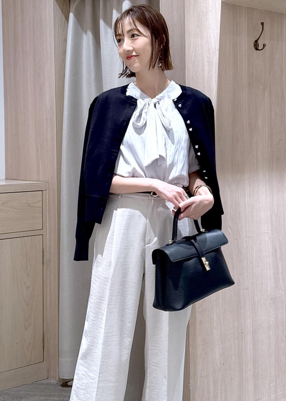 ブラック系のハンドバッグ、ブラック系のカーディガン/ボレロ、ブラック系のパンプスを着用したレディースの春コーディネートの5枚目の写真