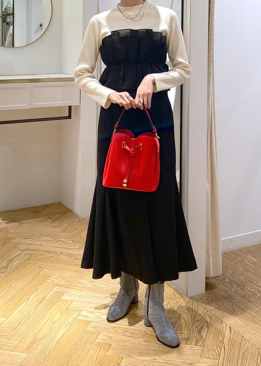 シルバー系のブーツ、ブラック系のスカート、ホワイト系のニット/セーターを着用したレディースの冬コーディネートの6枚目の写真