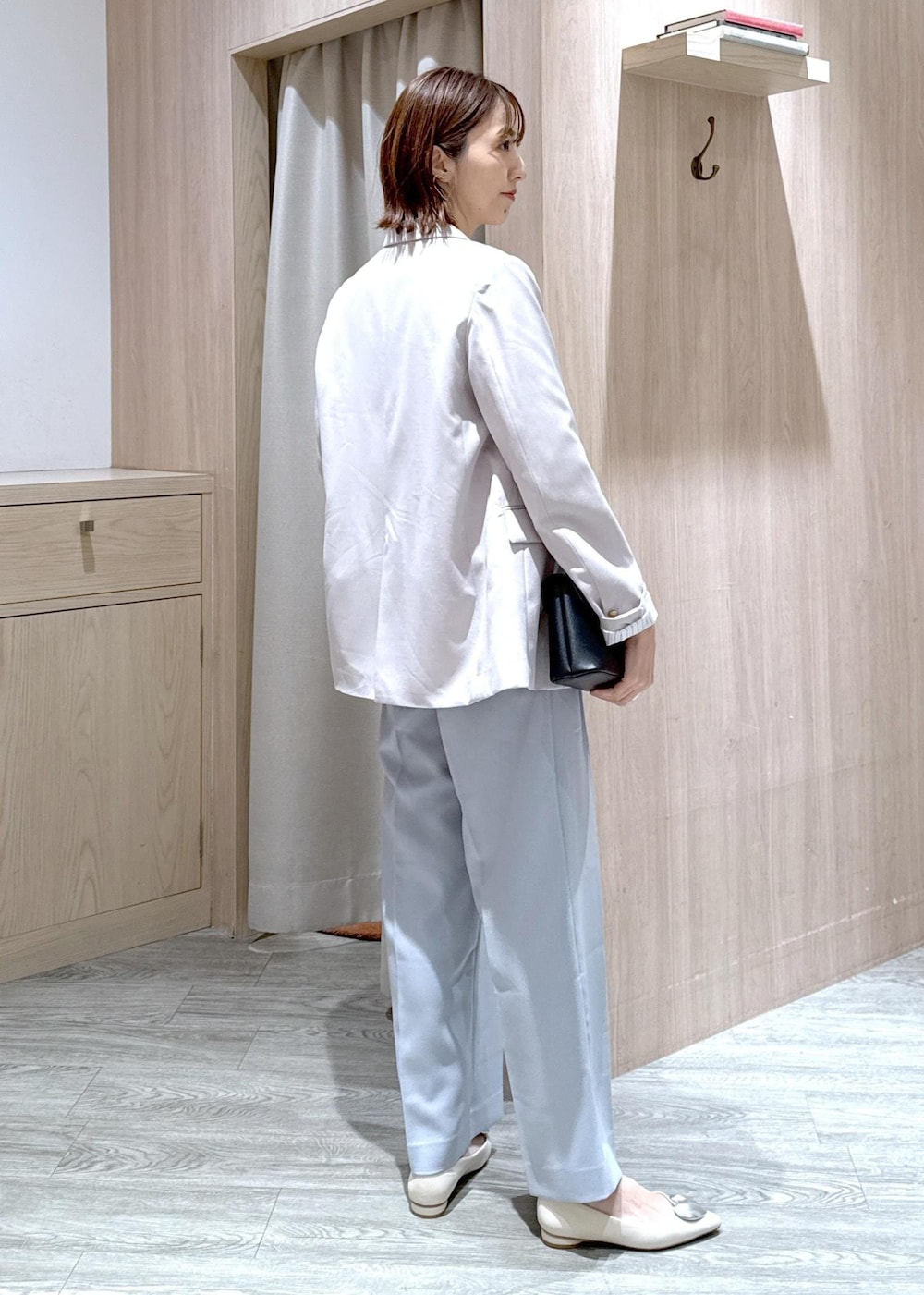 ブラック系のショルダーバッグ、ブルー系のスラックス、ベージュ系のテーラードジャケットを着用したレディースの春コーディネートの2枚目の写真