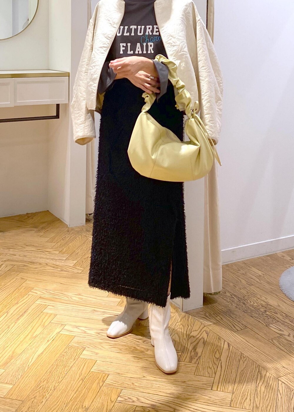 ホワイト系のブーツ、ブラック系のスカート、ホワイト系のブルゾンを着用したレディースの秋コーディネートの7枚目の写真