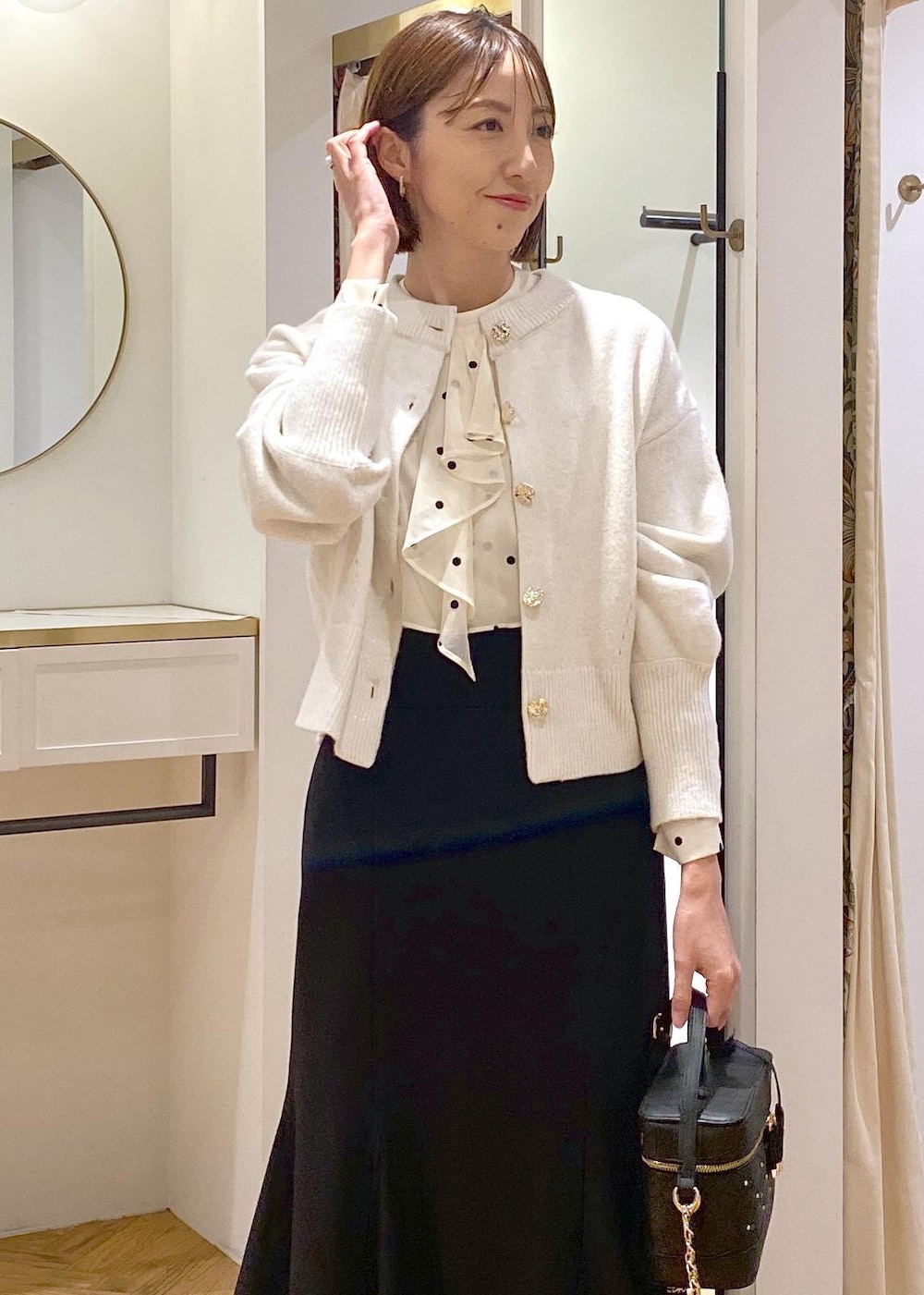 ホワイト系のカーディガン/ボレロ、ブラック系のスカート、ブラック系のパンプスを着用したレディースの冬コーディネートの6枚目の写真