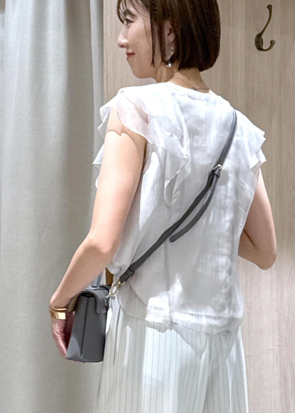 グレー系のショルダーバッグ、シルバー系のパンプス、ベージュ系のシャツ/ブラウスを着用したレディースの夏コーディネートの9枚目の写真