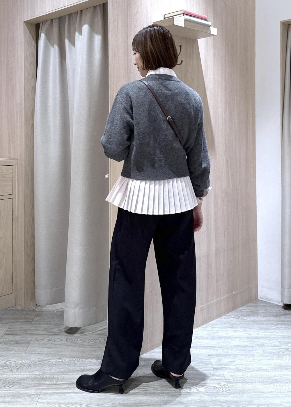 ブラウン系のショルダーバッグ、ブラック系のスラックス、グレー系のカーディガン/ボレロを着用したレディースの秋コーディネートの5枚目の写真