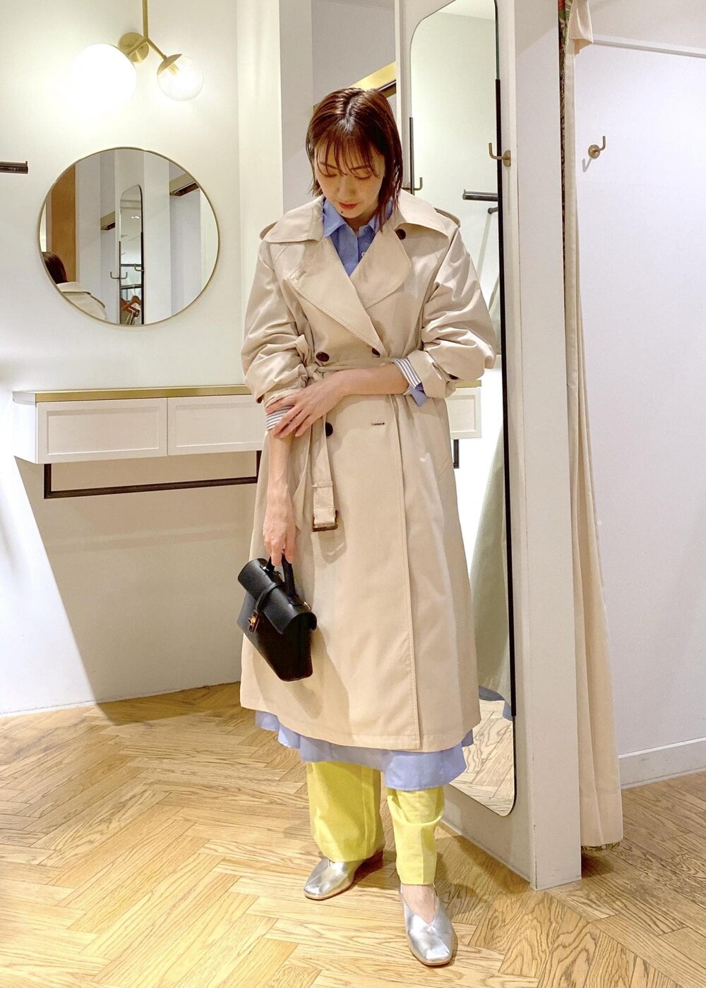 シルバー系のパンプス、ブルー系のシャツワンピース、ホワイト系のトレンチコートを着用したレディースの春コーディネートの4枚目の写真