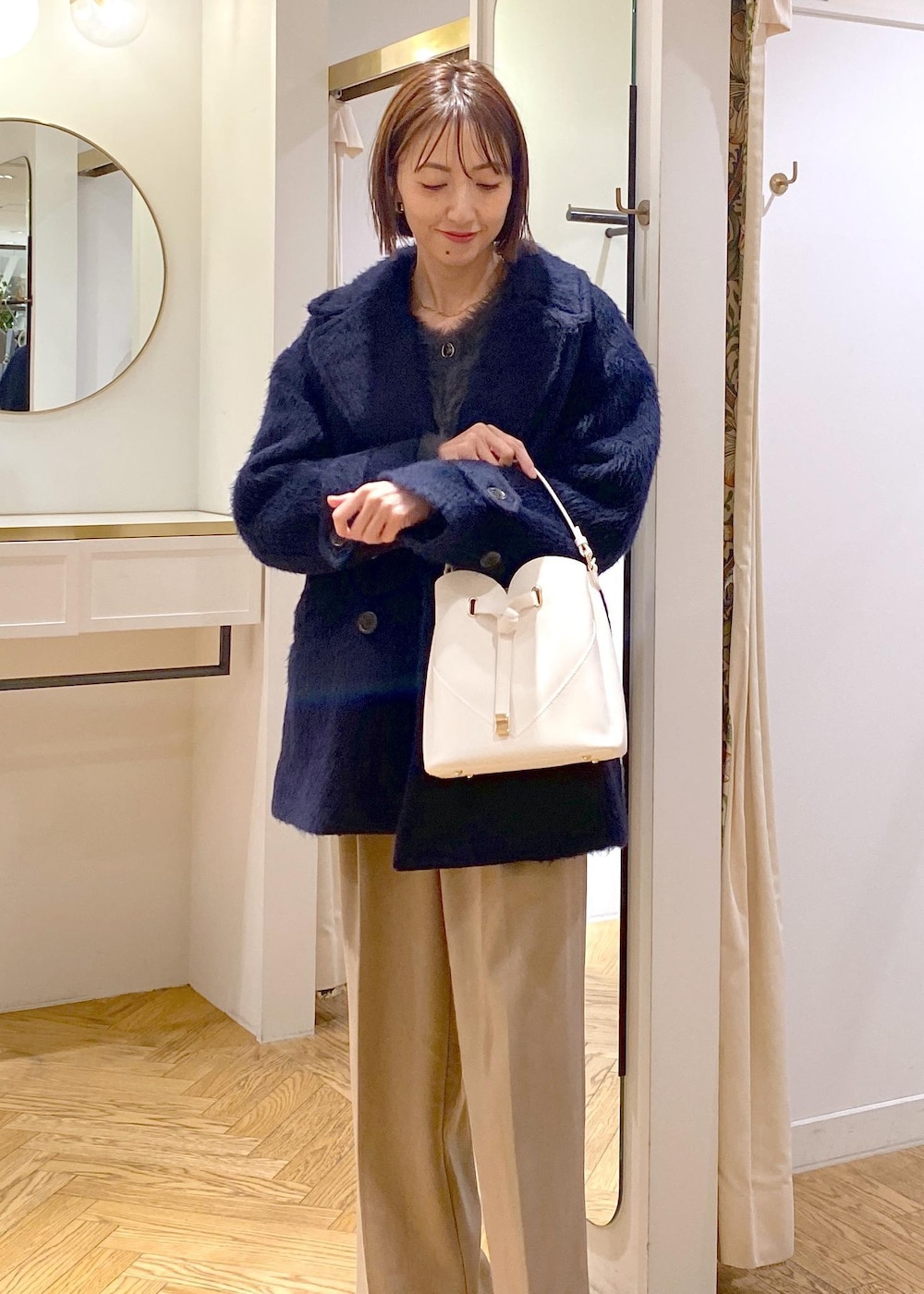 ホワイト系のショルダーバッグ、ベージュ系のスラックス、グレー系のカーディガン/ボレロを着用したレディースの冬コーディネートの6枚目の写真