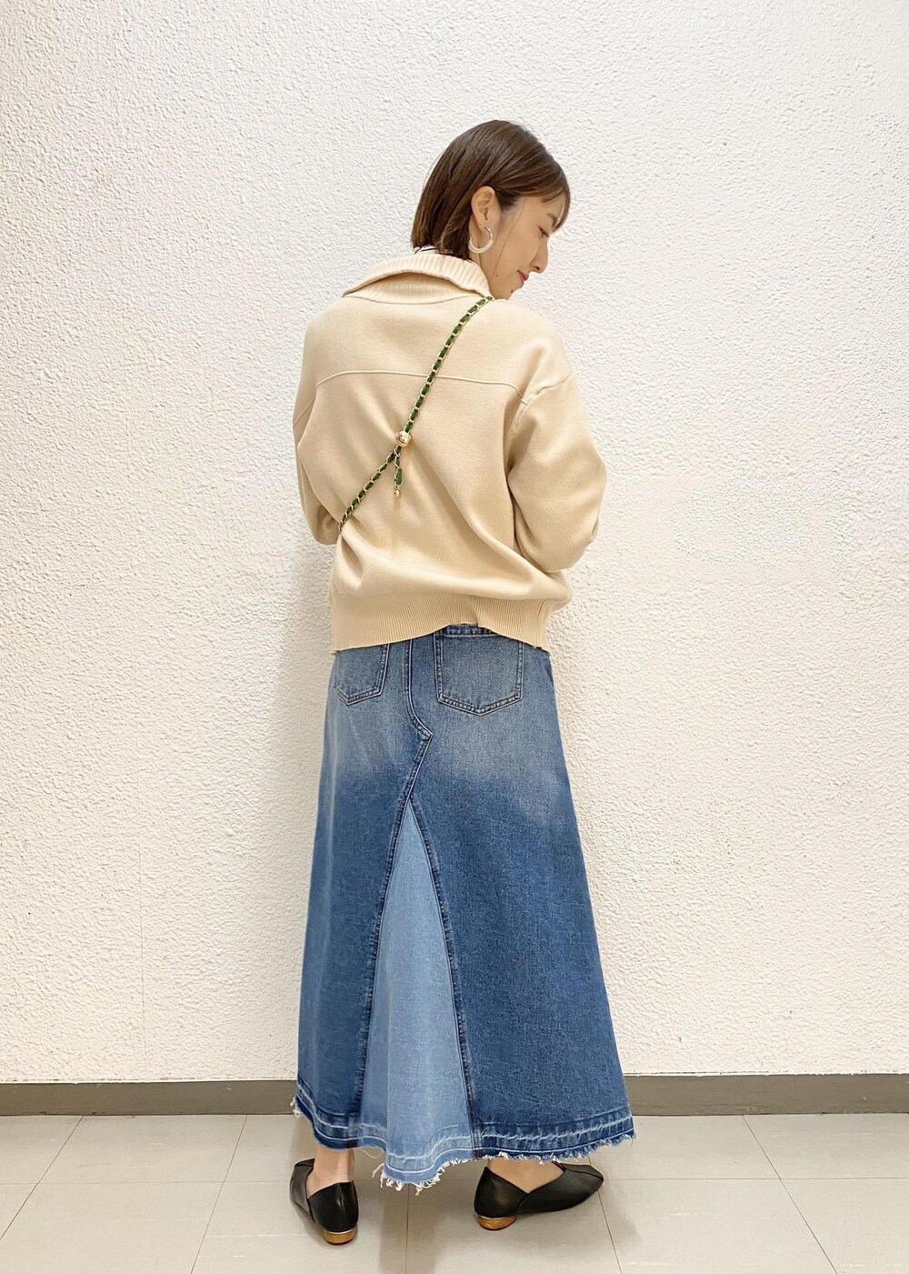 グリーン系のショルダーバッグ、ホワイト系のニット/セーター、ブルー系のデニムスカートを着用したレディースの冬コーディネートの2枚目の写真