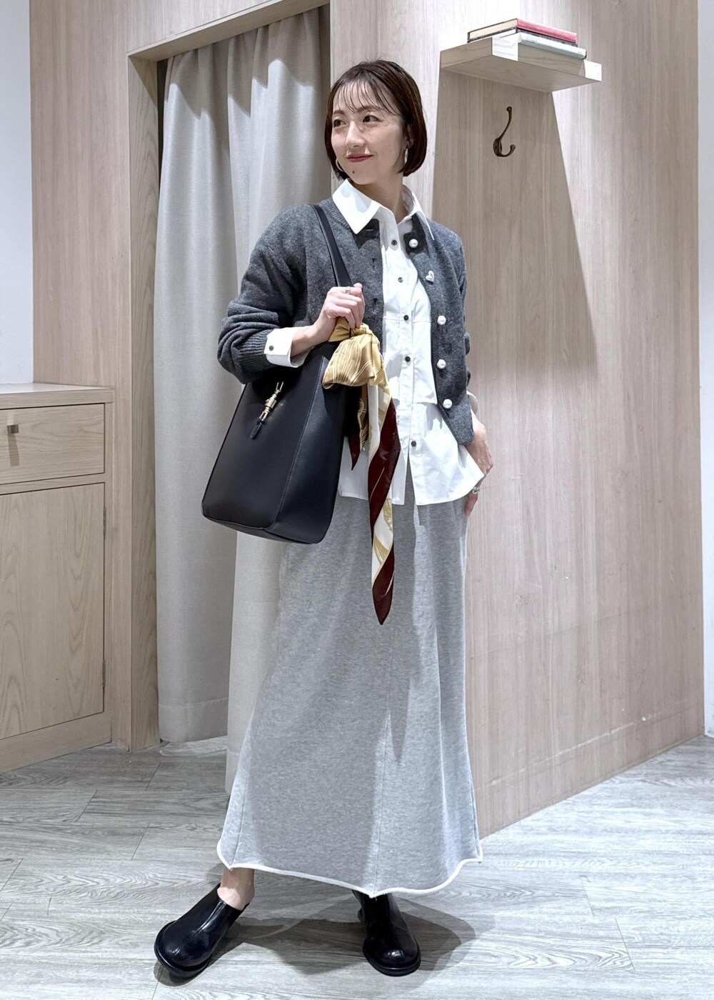 ブラック系のトートバッグ、グレー系のスカート、ホワイト系のシャツ/ブラウスを着用したレディースの秋コーディネートの5枚目の写真