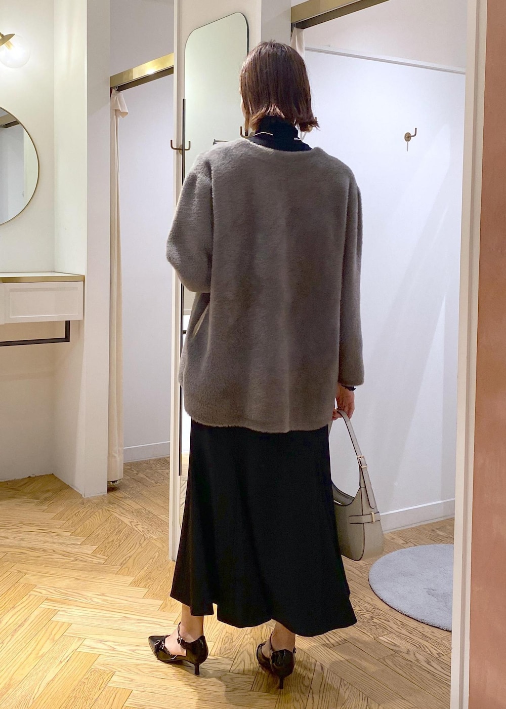 ブラック系のパンプス、ブラック系のスカート、ブラウン系のその他アウターを着用したレディースの秋コーディネートの2枚目の写真