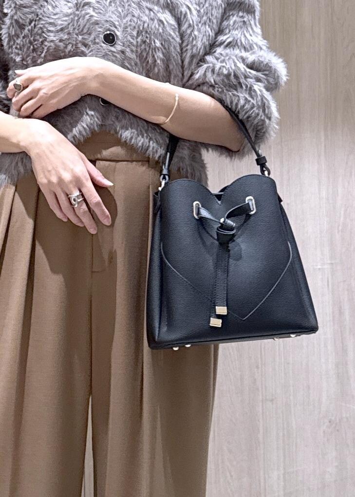 ブラック系のショルダーバッグ、グレー系のカーディガン/ボレロ、ブラック系のブーツを着用したレディースの秋コーディネートの5枚目の写真