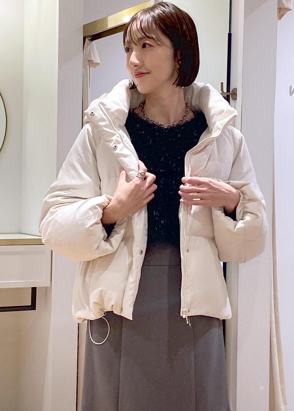 ホワイト系のブーツ、グレー系のスカート、ホワイト系のダウンジャケット/コートを着用したレディースの冬コーディネートの5枚目の写真