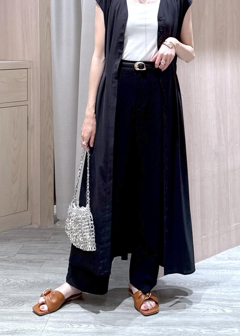 ホワイト系のタンクトップ、ブラック系のスラックス、シルバー系のハンドバッグを着用したレディースの春コーディネートの5枚目の写真