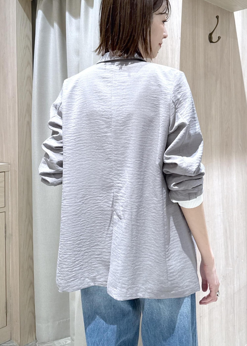 ブラック系のショルダーバッグ、ブルー系のデニムパンツ、グレー系のテーラードジャケットを着用したレディースの春コーディネートの6枚目の写真