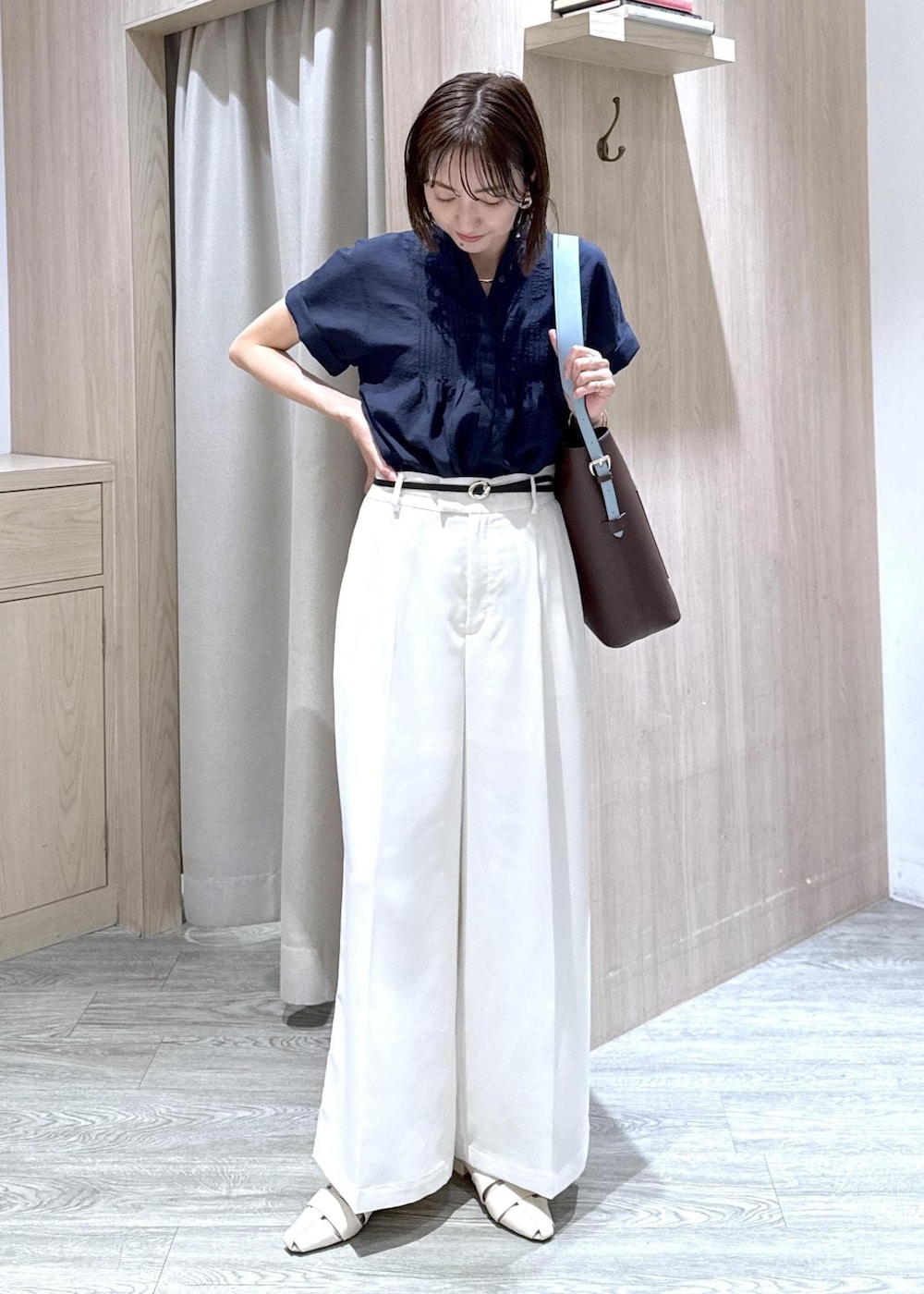 ブラウン系のトートバッグ、ホワイト系のパンプス、ブルー系のシャツ/ブラウスを着用したレディースの夏コーディネートの2枚目の写真
