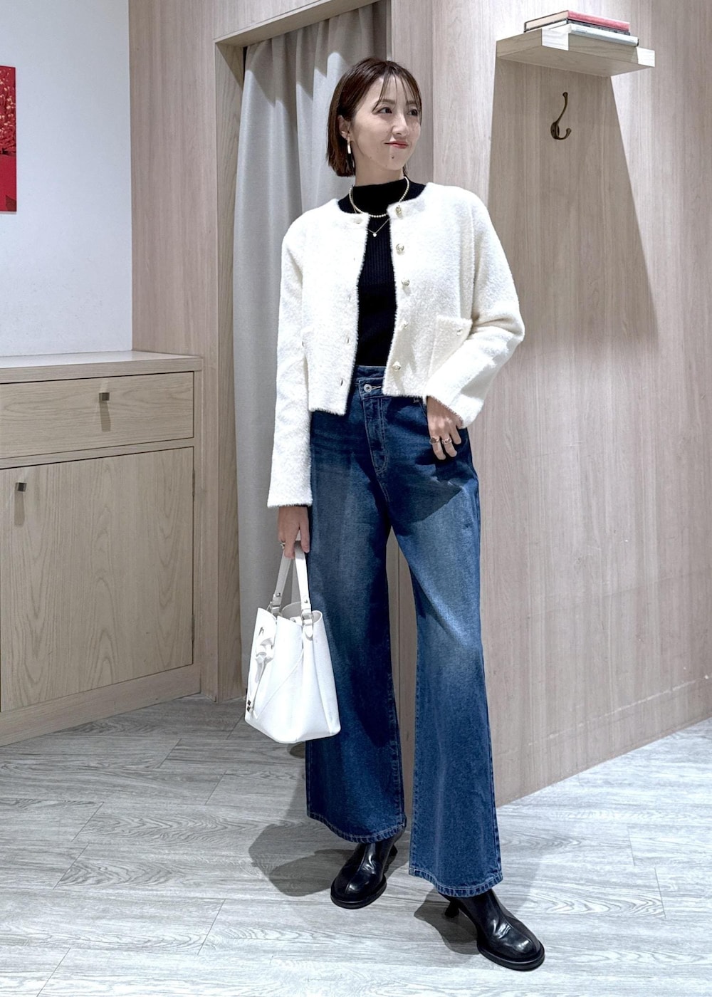 ホワイト系のショルダーバッグ、ブルー系のデニムパンツ、ブラック系のニット/セーターを着用したレディースの冬コーディネートの2枚目の写真