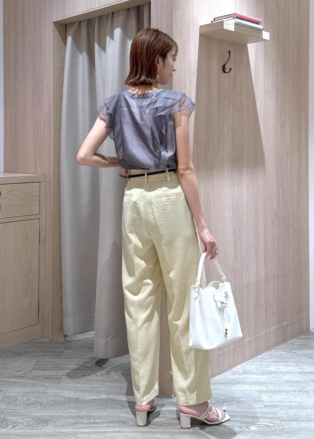 ホワイト系のショルダーバッグ、ホワイト系のサンダル、イエロー系のスラックスを着用したレディースの夏コーディネートの3枚目の写真