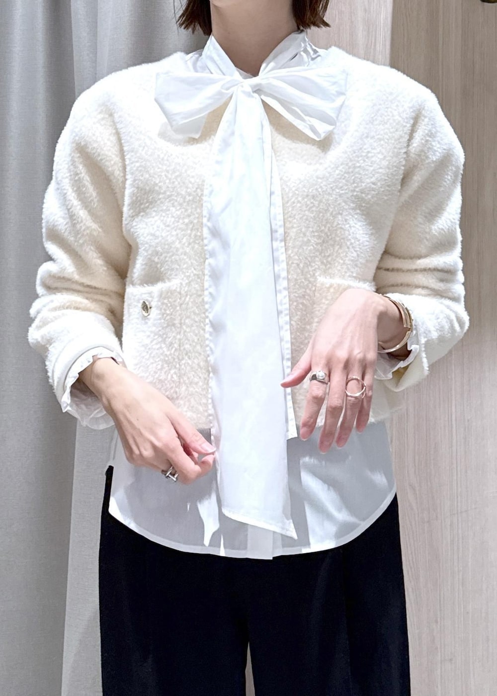 ブラック系のハンドバッグ、ブラック系のスラックス、ホワイト系のカーディガン/ボレロを着用したレディースの冬コーディネートの7枚目の写真