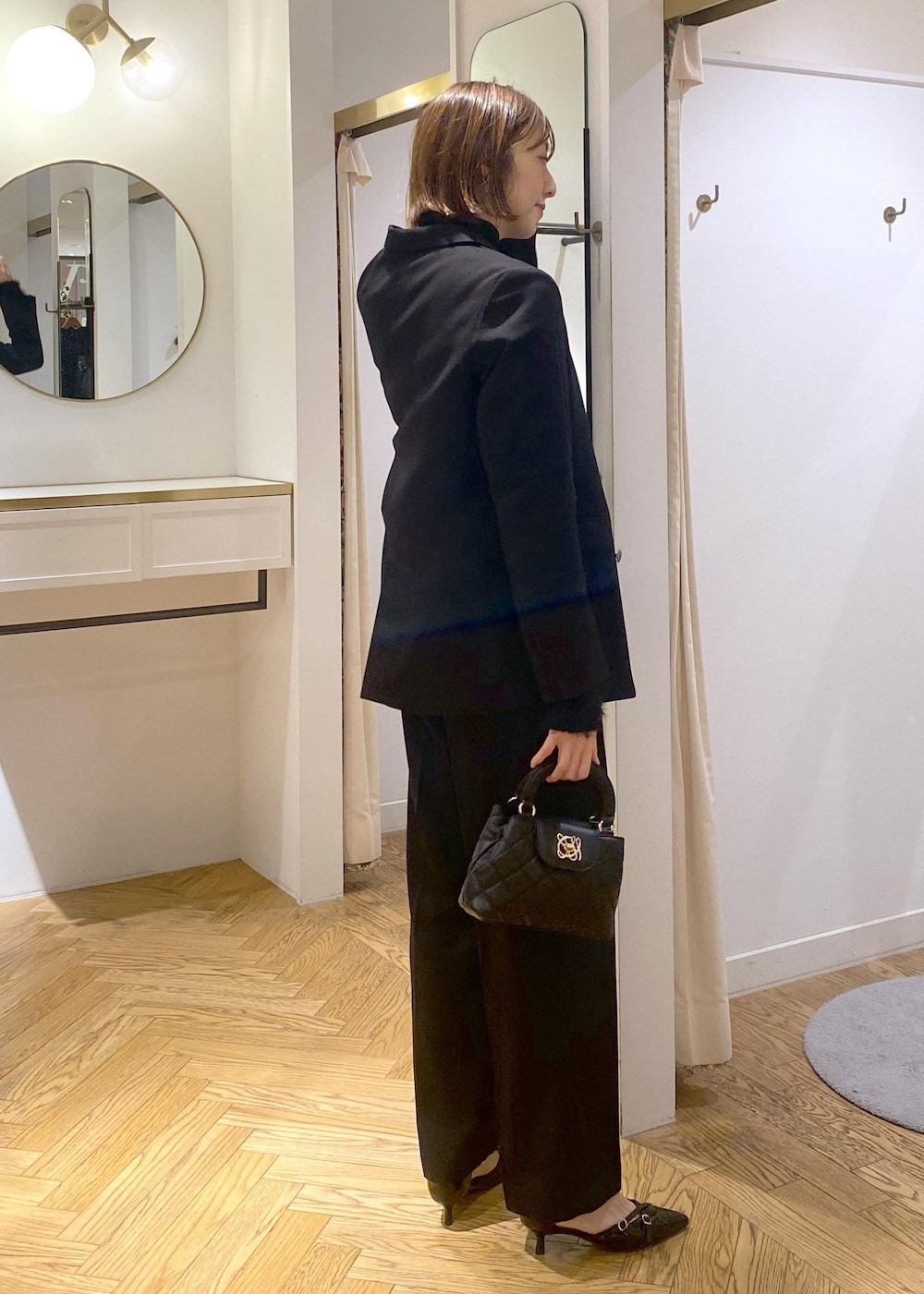 ブラック系のニット/セーター、ブラック系のスラックス、ブラック系のテーラードジャケットを着用したレディースの冬コーディネートの4枚目の写真