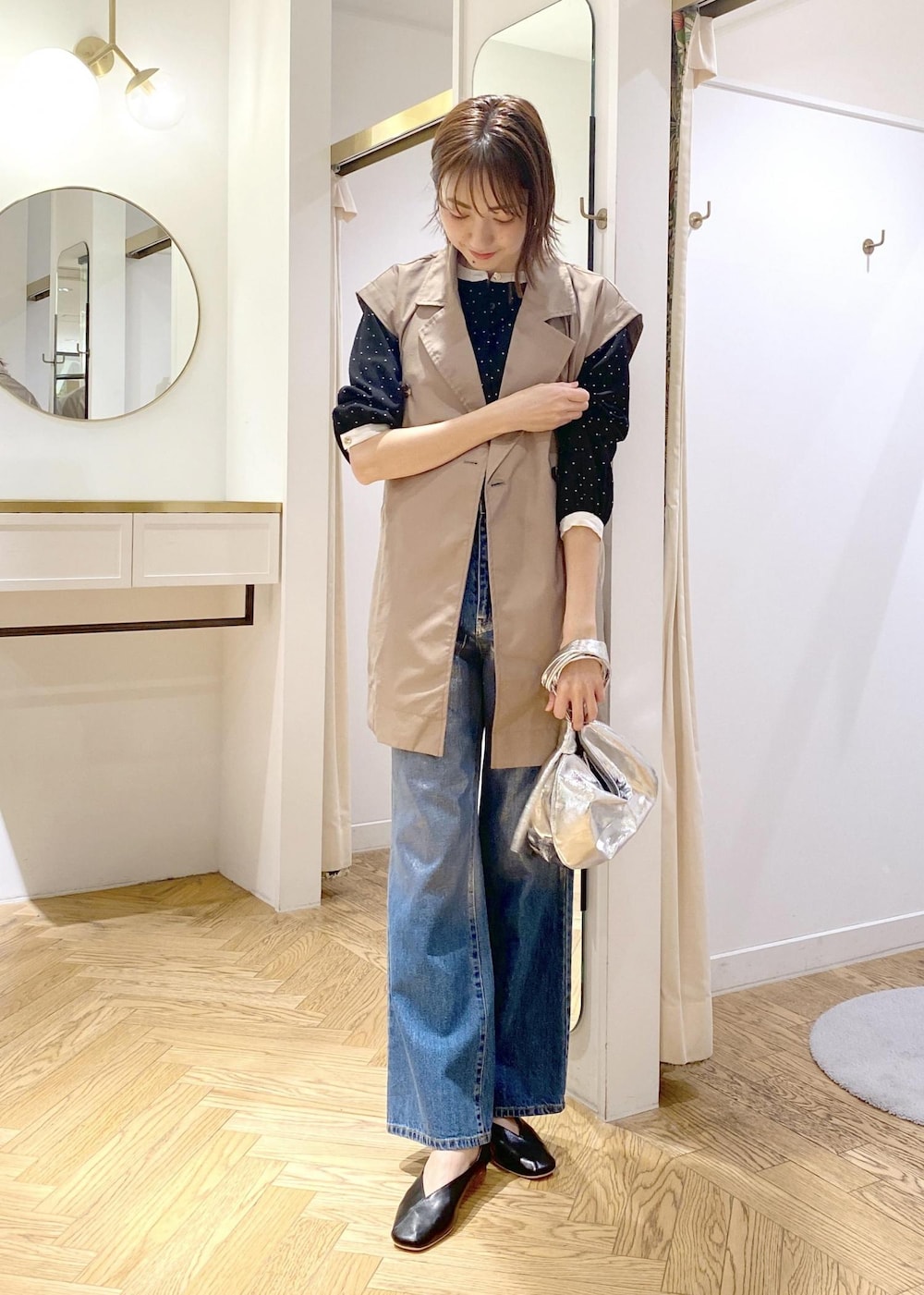 ブラック系のパンプス、グリーン系のトレンチコート、ブルー系のデニムパンツを着用したレディースの春コーディネートの2枚目の写真