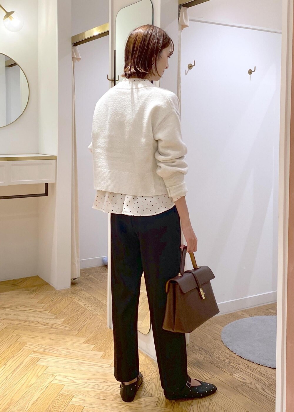 ブラウン系のハンドバッグ、ブラック系のバレエシューズ、ブラック系のスラックスを着用したレディースの秋コーディネートの3枚目の写真