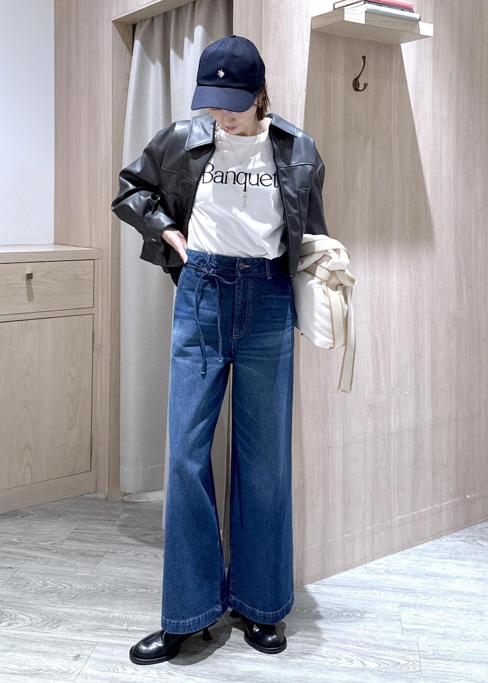 ホワイト系のトートバッグ、ブラック系のブルゾン、ホワイト系のTシャツ/カットソーを着用したレディースの冬コーディネートの2枚目の写真