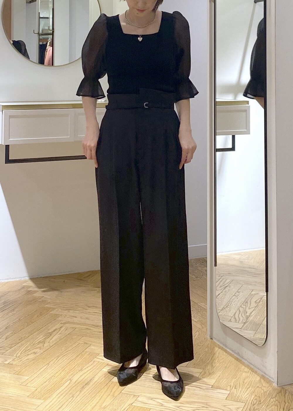 ブラック系のパンプス、ブラック系のショルダーバッグ、ブラック系のスラックスを着用したレディースの夏コーディネートの3枚目の写真