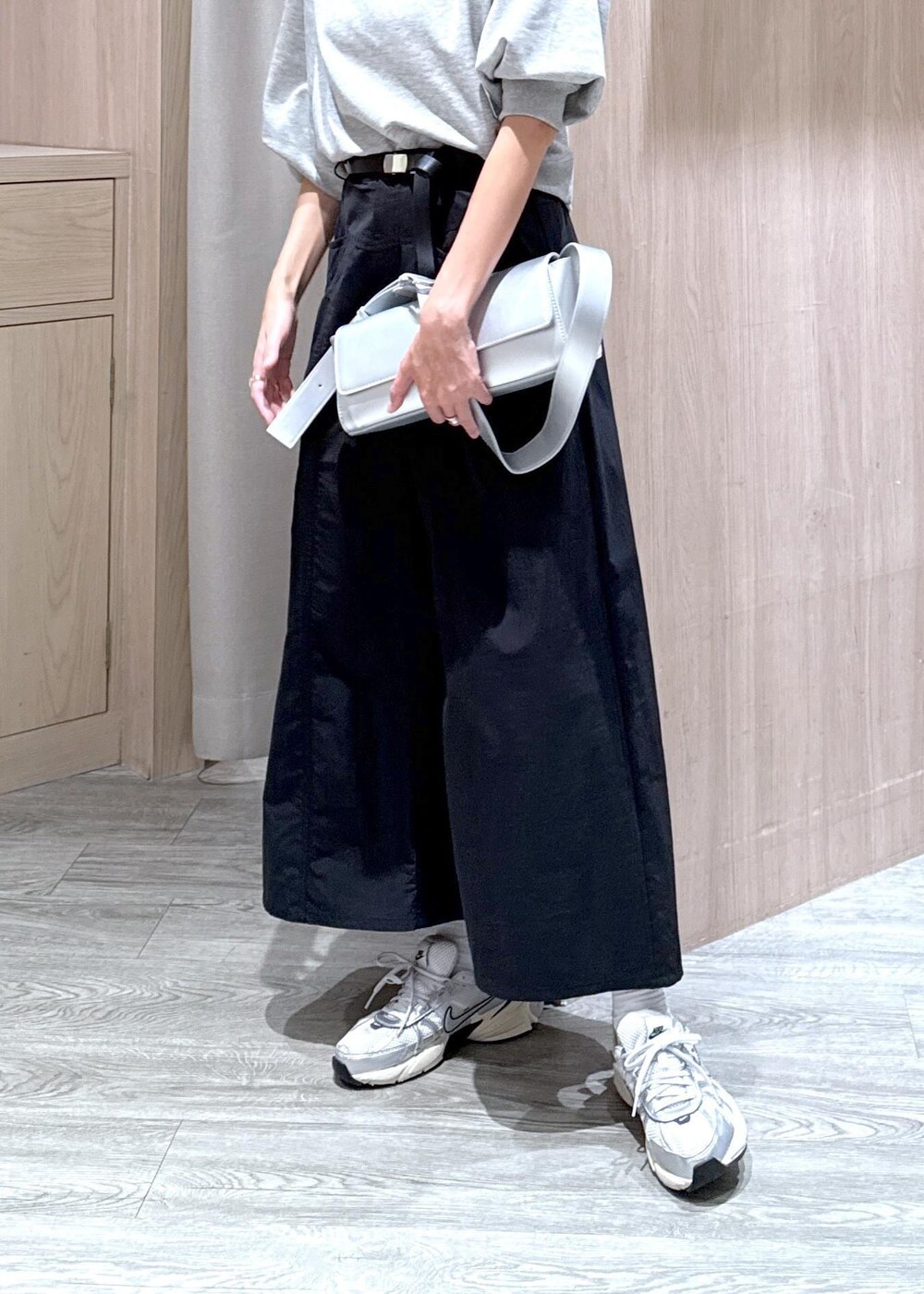 シルバー系のショルダーバッグ、ブラック系のスカート、ホワイト系のキャミソールを着用したレディースの秋コーディネートの4枚目の写真