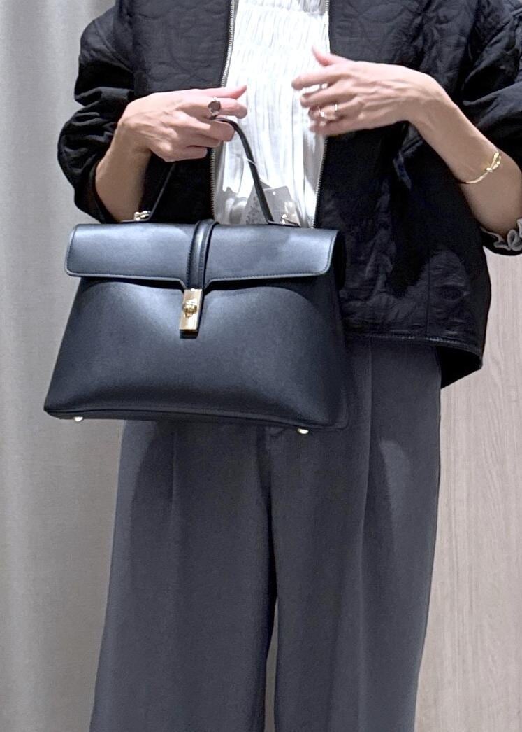 ブラック系のハンドバッグ、グレー系のスラックス、ホワイト系のシャツ/ブラウスを着用したレディースの秋コーディネートの6枚目の写真