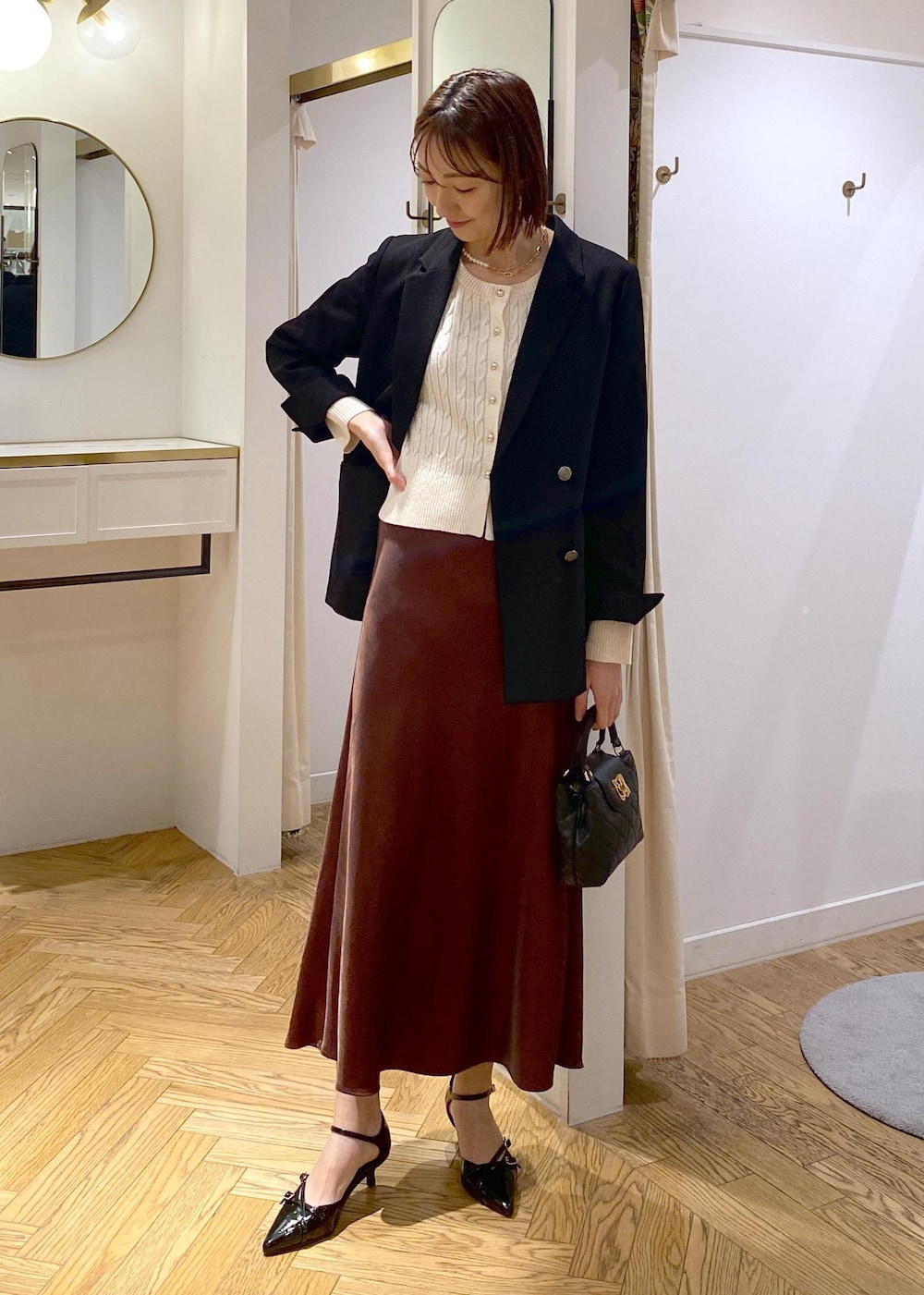 ブラック系のテーラードジャケット、ブラック系のパンプス、ブラウン系のスカートを着用したレディースの冬コーディネートの5枚目の写真