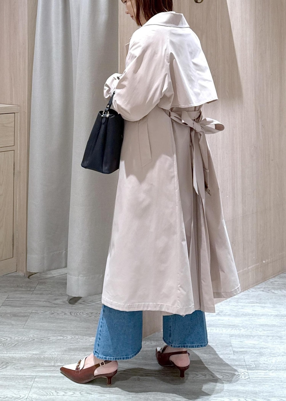 ブラック系のショルダーバッグ、ベージュ系のトレンチコート、ホワイト系のカーディガン/ボレロを着用したレディースの春コーディネートの4枚目の写真