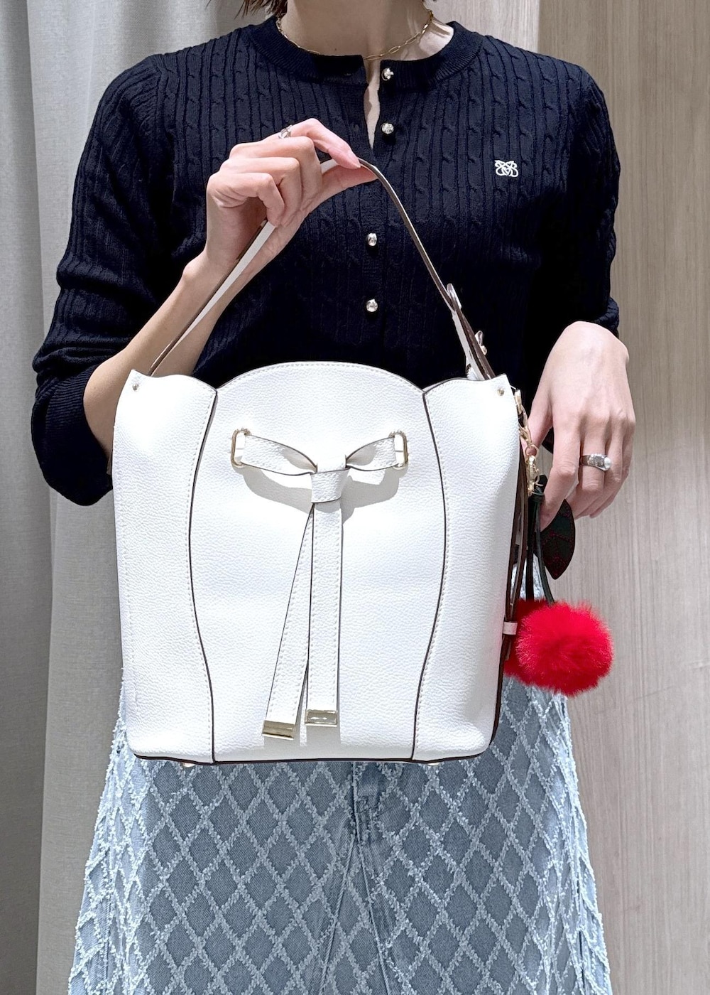 ホワイト系のショルダーバッグ、ブルー系のカーディガン/ボレロ、ブルー系のデニムスカートを着用したレディースの冬コーディネートの9枚目の写真