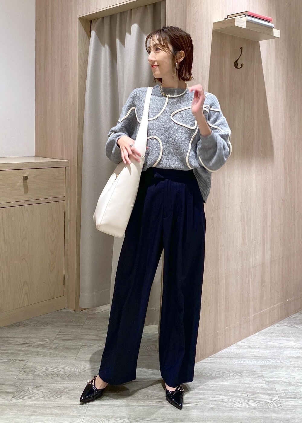 ブラック系のパンプス、グレー系のニット/セーター、ホワイト系のトートバッグを着用したレディースの冬コーディネートの4枚目の写真