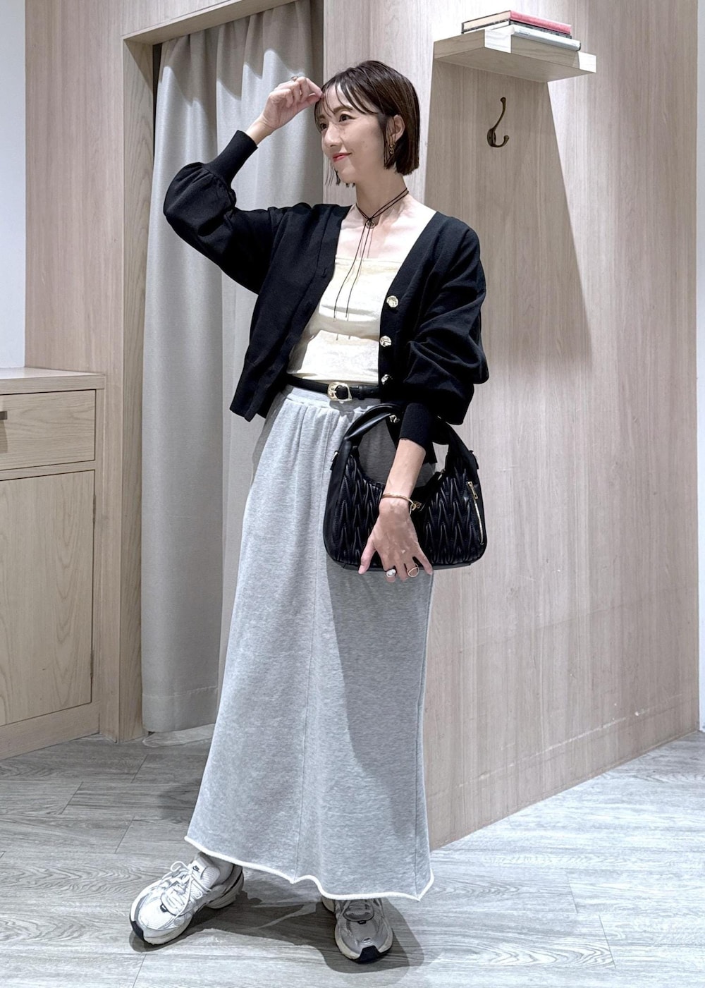 グレー系のスカート、ホワイト系のキャミソール、ブラック系のカーディガン/ボレロを着用したレディースの秋コーディネートの2枚目の写真
