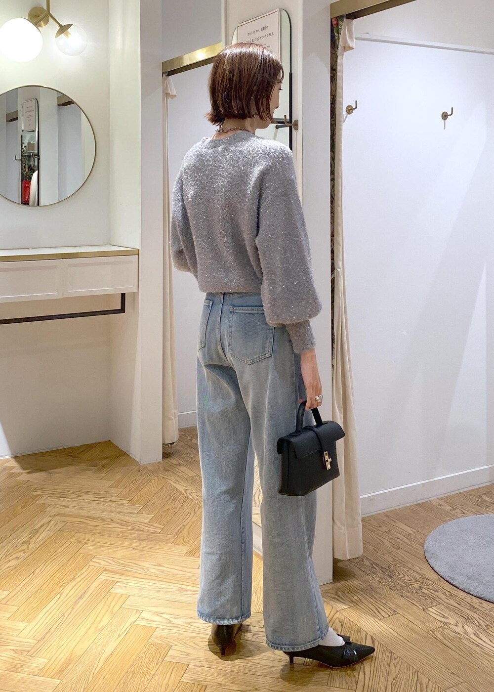 ブラック系のパンプス、グレー系のニット/セーター、ブルー系のデニムパンツを着用したレディースの冬コーディネートの5枚目の写真