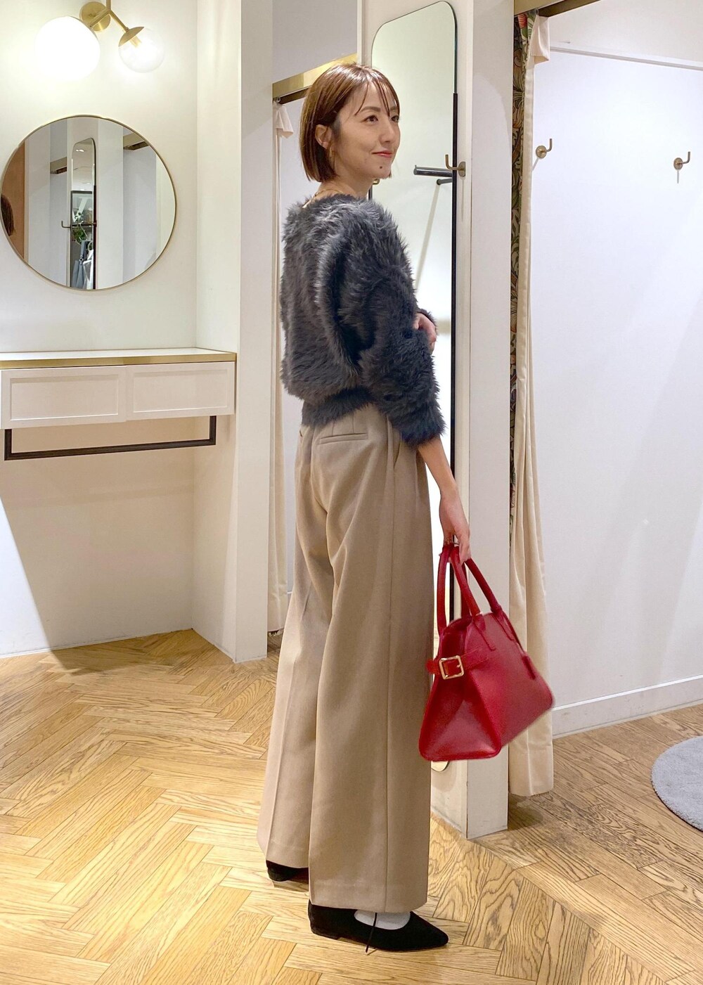 レッド系のトートバッグ、ベージュ系のスラックス、グレー系のカーディガン/ボレロを着用したレディースの冬コーディネートの5枚目の写真