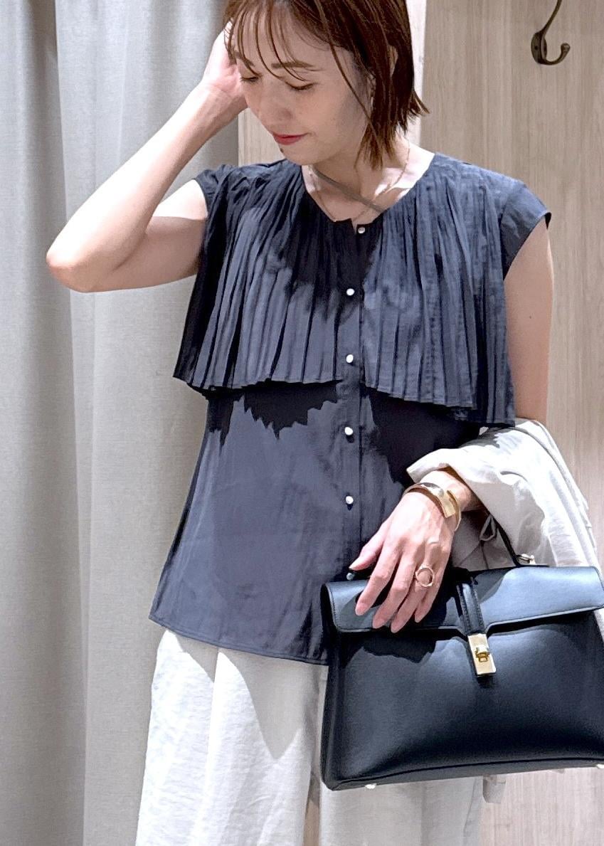 ブラック系のハンドバッグ、ブラック系のパンプス、ホワイト系のスラックスを着用したレディースの夏コーディネートの8枚目の写真