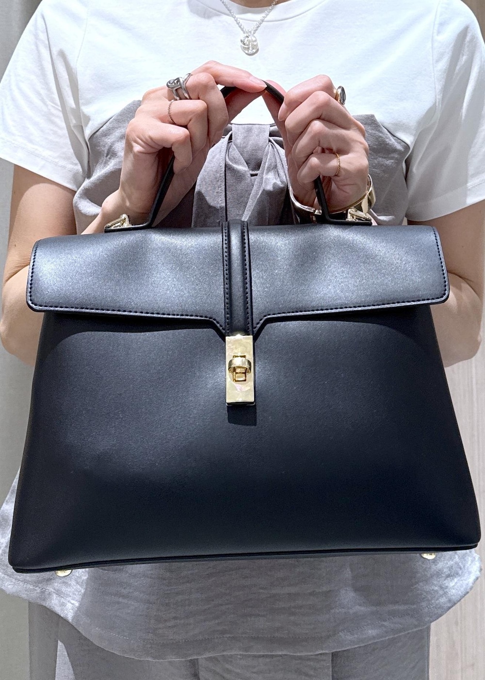 ブラック系のハンドバッグ、ブラック系のパンプス、グレー系のTシャツ/カットソーを着用したレディースの春コーディネートの10枚目の写真