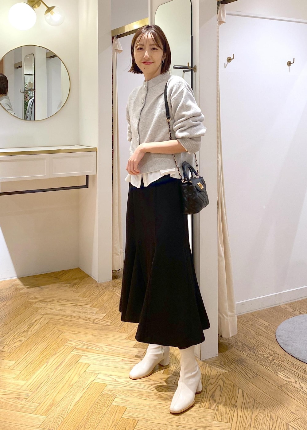 ホワイト系のシャツ/ブラウス、グレー系のカーディガン/ボレロ、ホワイト系のブーツを着用したレディースの冬コーディネートの7枚目の写真