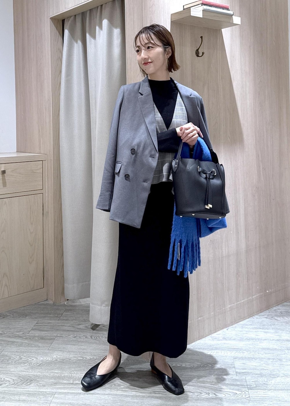 グレー系のテーラードジャケット、ブラック系のショルダーバッグ、ブラック系のワンピースを着用したレディースの秋コーディネートの10枚目の写真