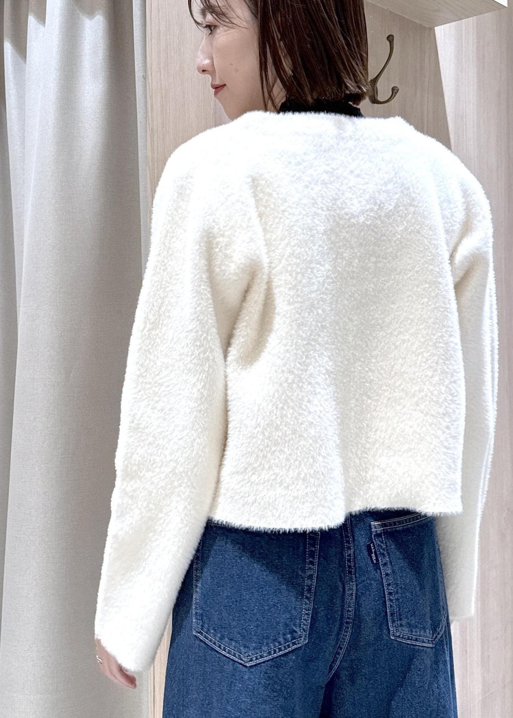 ホワイト系のショルダーバッグ、ブルー系のデニムパンツ、ブラック系のニット/セーターを着用したレディースの冬コーディネートの7枚目の写真