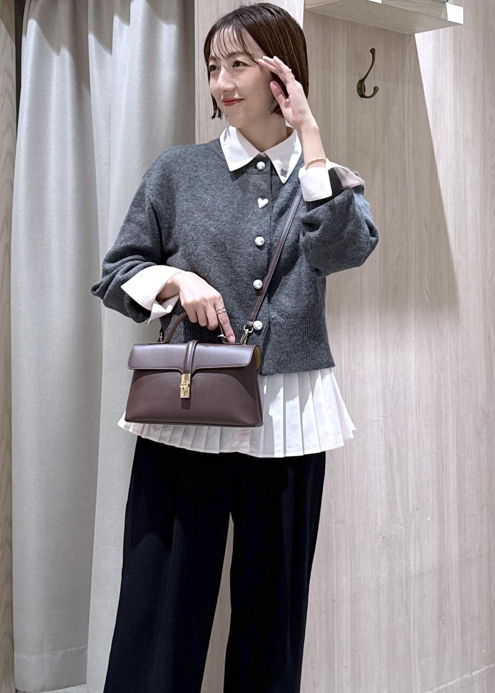 ブラウン系のショルダーバッグ、ブラック系のスラックス、グレー系のカーディガン/ボレロを着用したレディースの秋コーディネートの6枚目の写真