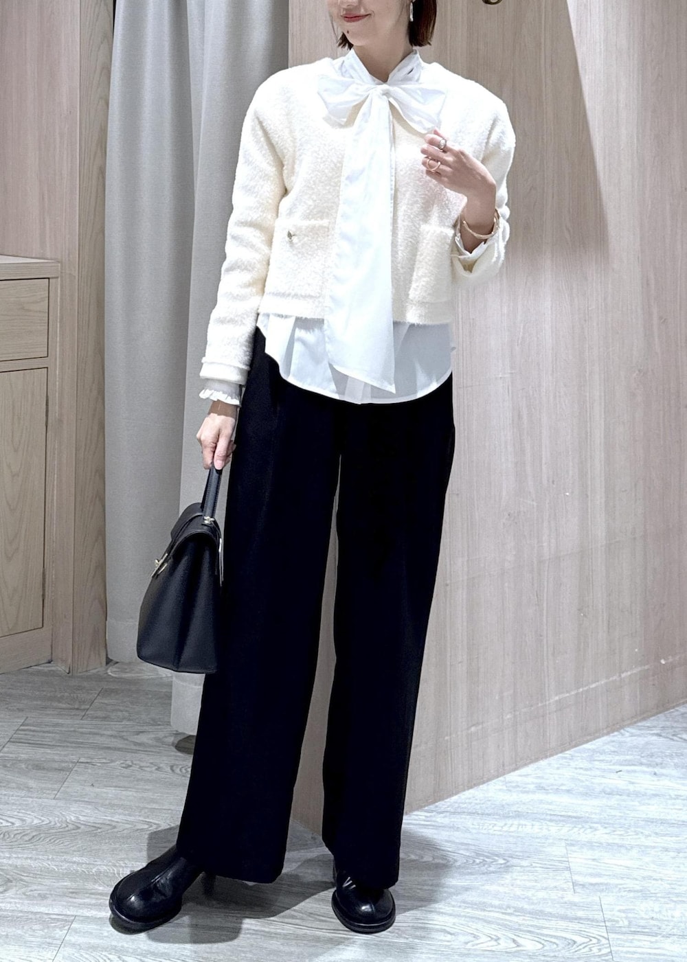 ブラック系のハンドバッグ、ブラック系のスラックス、ホワイト系のカーディガン/ボレロを着用したレディースの冬コーディネートの3枚目の写真