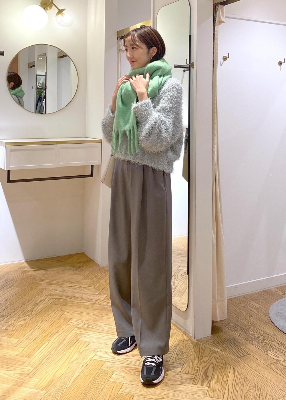 ベージュ系のショルダーバッグ、グレー系のスラックス、グリーン系のニット/セーターを着用したレディースの冬コーディネートの2枚目の写真