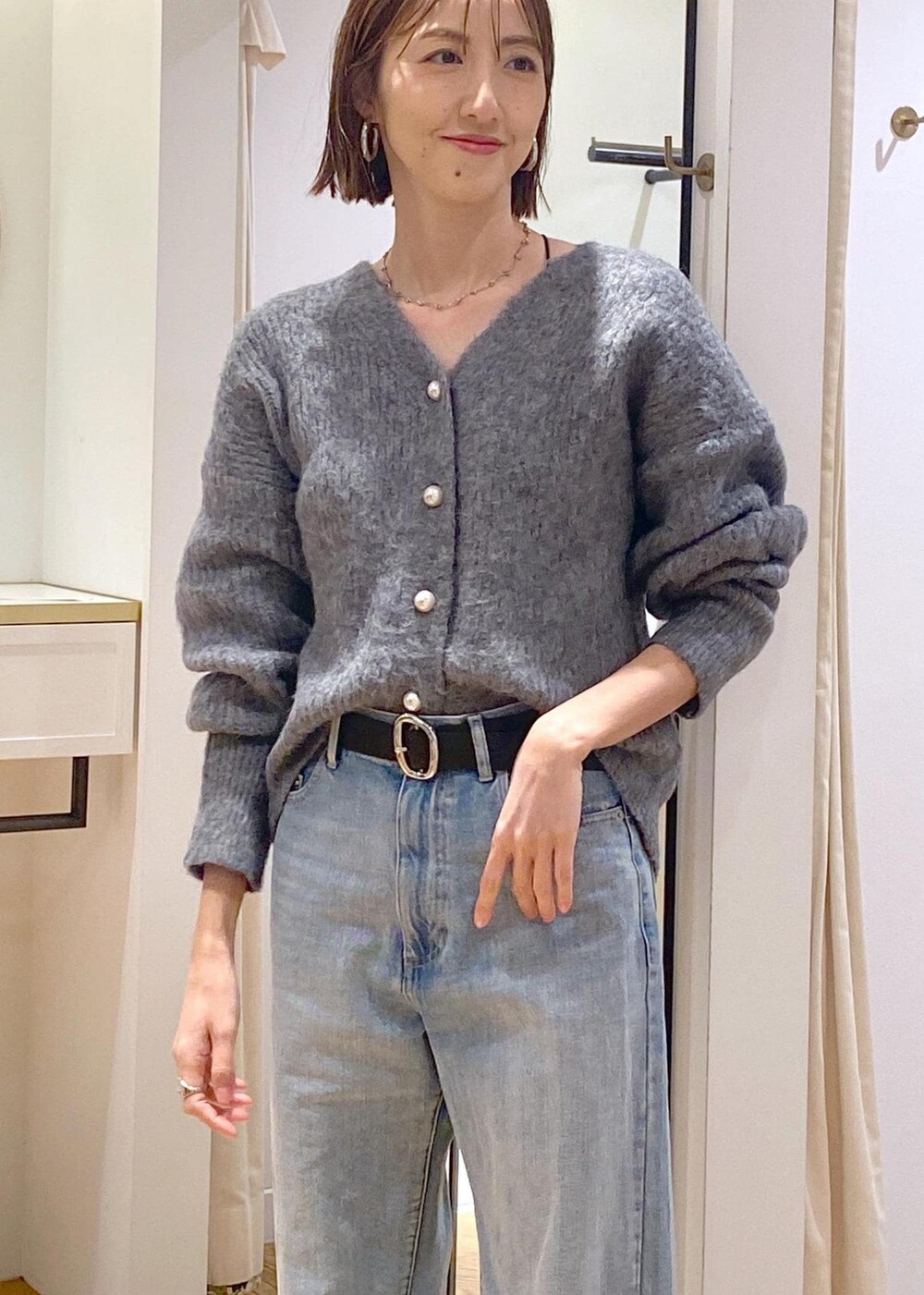 シルバー系のショルダーバッグ、ブルー系のデニムパンツ、グレー系のカーディガン/ボレロを着用したレディースの冬コーディネートの9枚目の写真