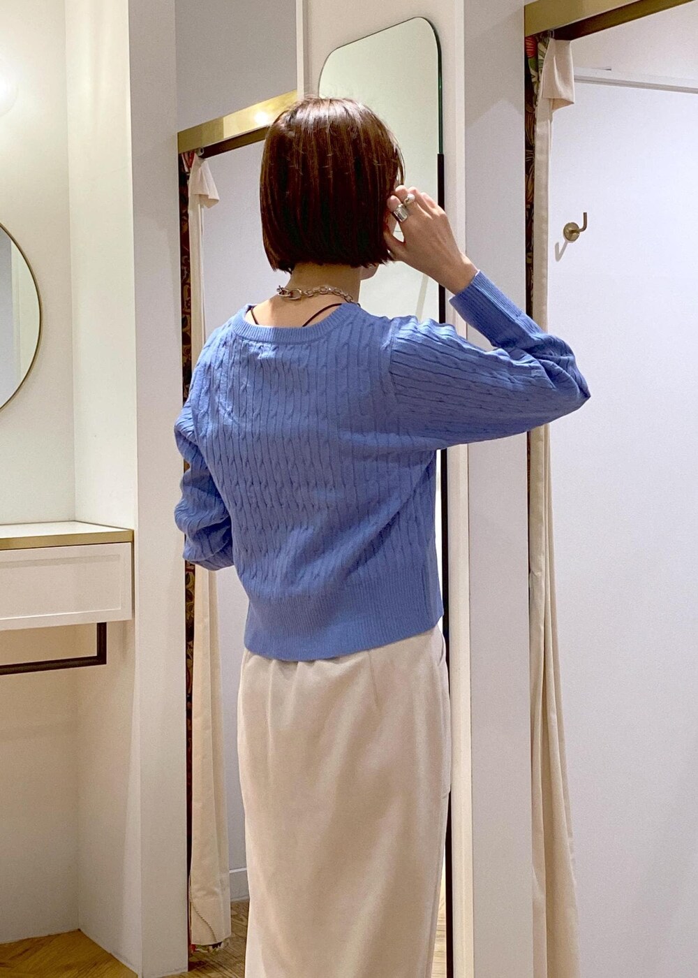 ホワイト系のショルダーバッグ、ブルー系のカーディガン/ボレロ、ベージュ系のスカートを着用したレディースの冬コーディネートの6枚目の写真