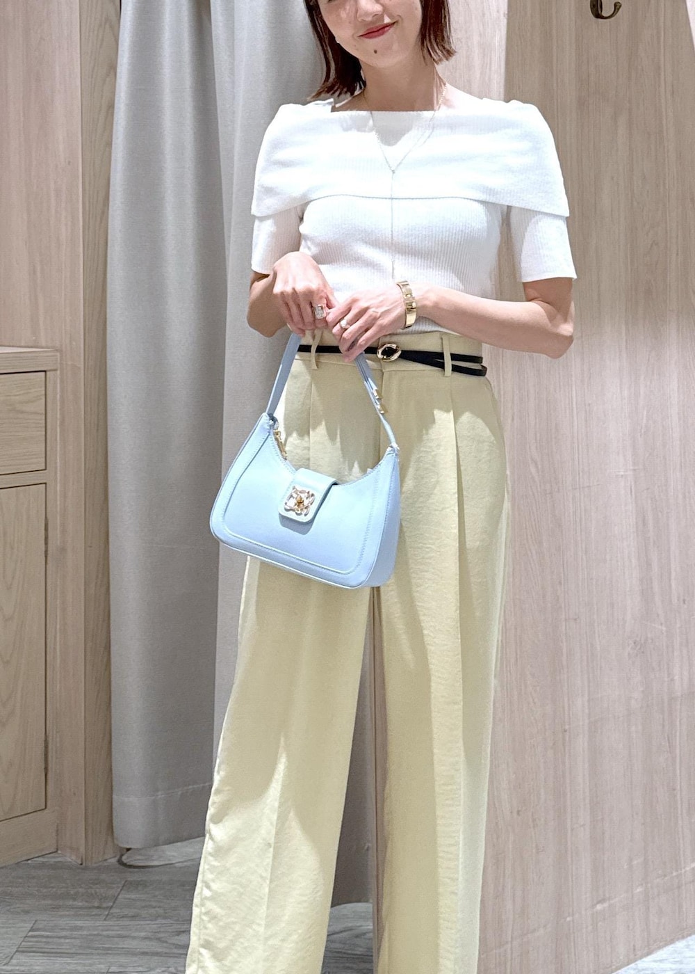 ブルー系のハンドバッグ、ブラック系のサンダル、イエロー系のスラックスを着用したレディースの夏コーディネートの7枚目の写真