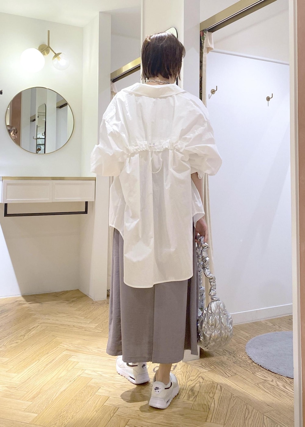 グレー系のスカート、ホワイト系のブルゾン、ホワイト系のTシャツ/カットソーを着用したレディースの春コーディネートの2枚目の写真