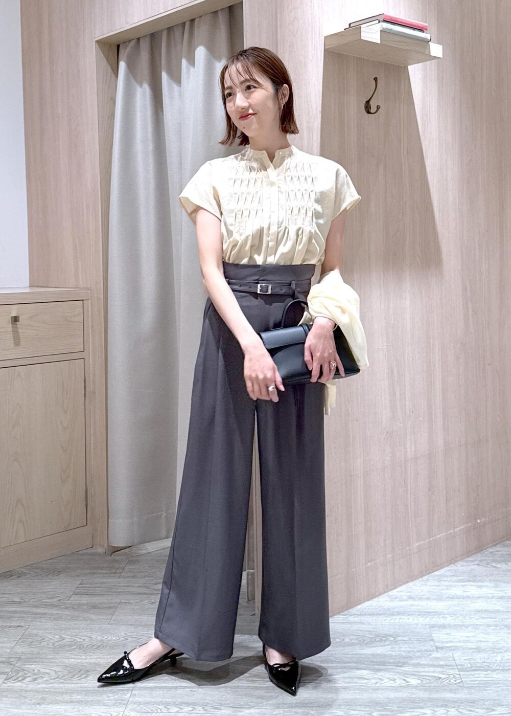 ブラック系のショルダーバッグ、ブラック系のパンプス、ホワイト系のカーディガン/ボレロを着用したレディースの春コーディネートの2枚目の写真