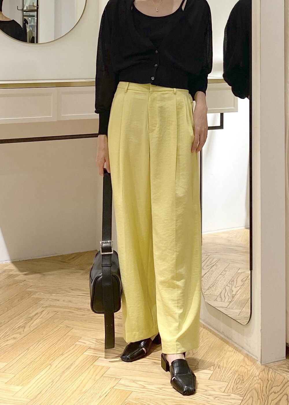 ブラック系のキャミソール、イエロー系のスラックス、ブラック系のショルダーバッグを着用したレディースの夏コーディネートの4枚目の写真