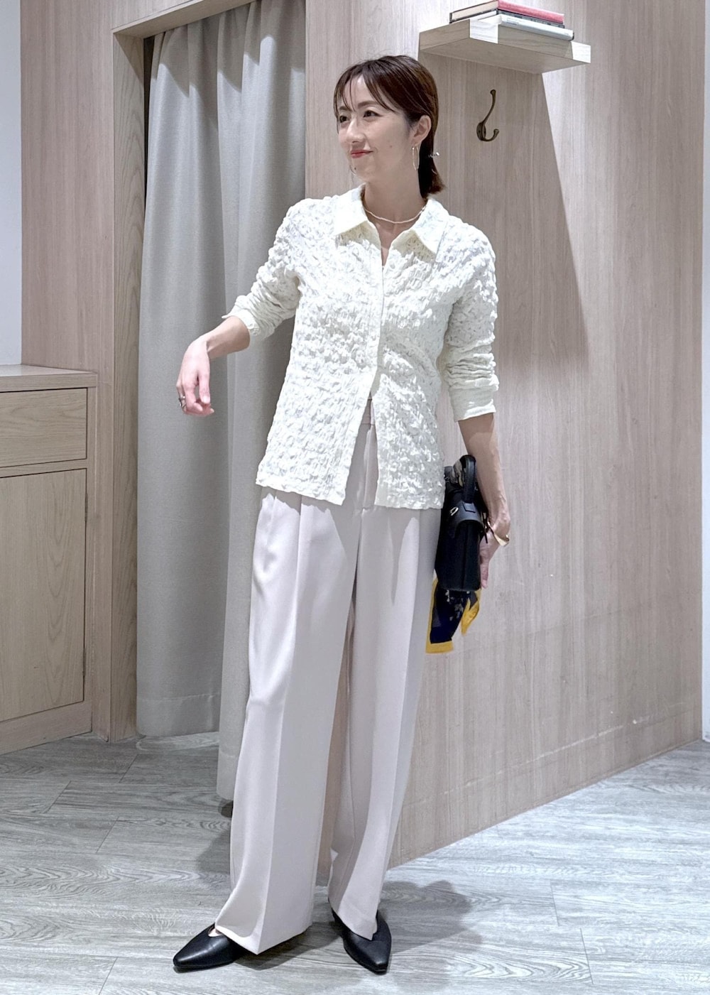 ベージュ系のその他パンツ、ホワイト系のカーディガン/ボレロ、ブラック系のショルダーバッグを着用したレディースの春コーディネートの3枚目の写真