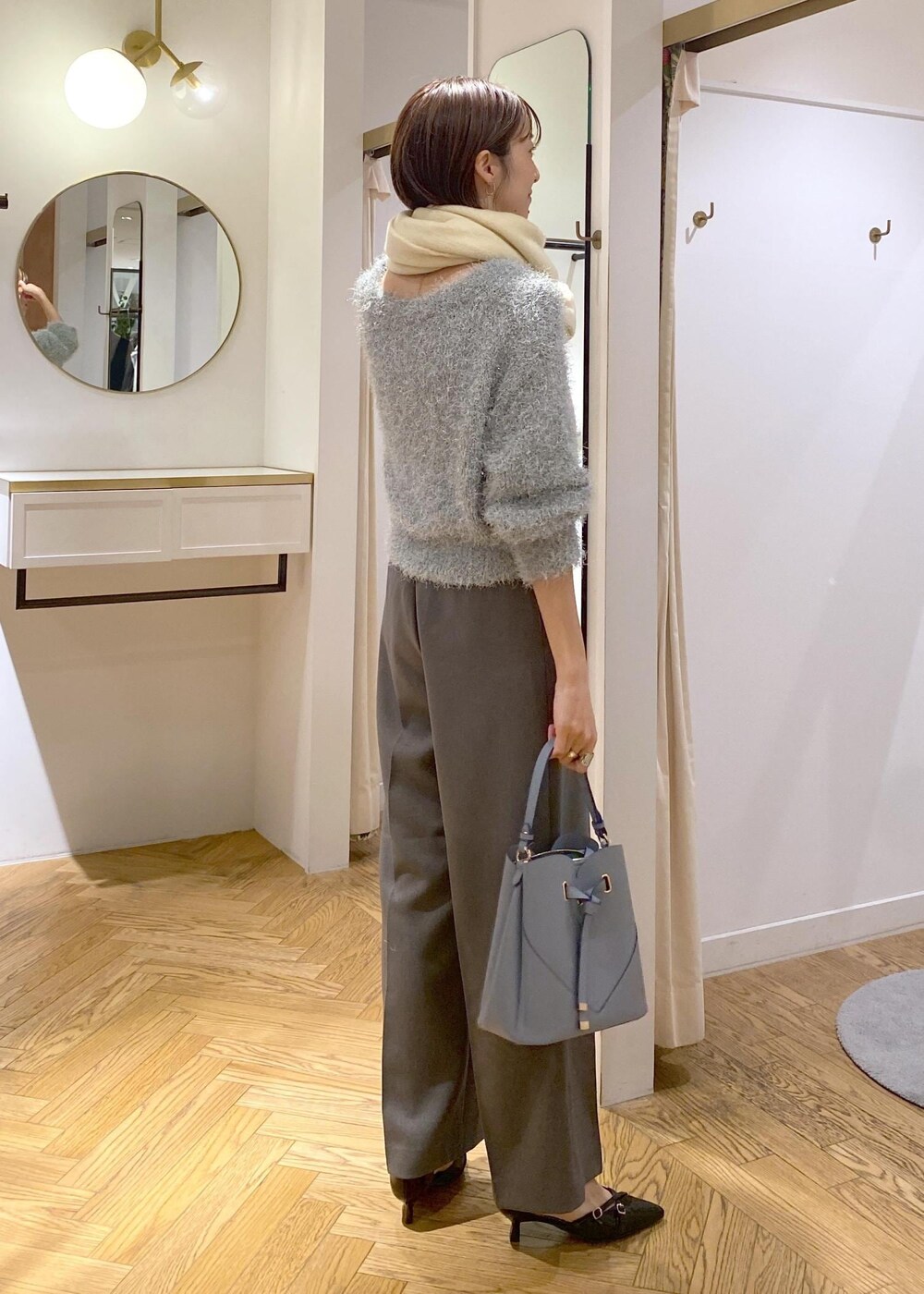 グレー系のスラックス、ブルー系のショルダーバッグ、ブラック系のパンプスを着用したレディースの冬コーディネートの4枚目の写真